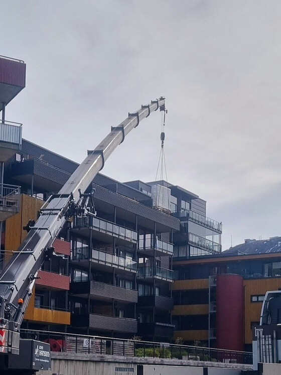 En krane som legger noe på taket til en bygning.