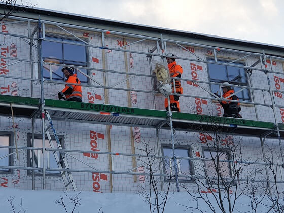 3 personer som arbeider med en bygning utendørs.