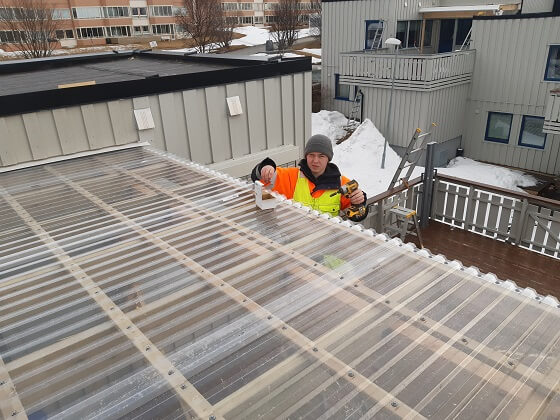 En mann som arbeider med en elektrisk skrutrekker på et tak utendørs.